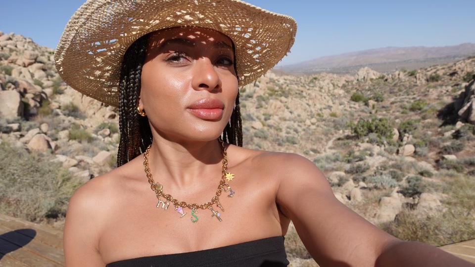 A woman in a straw hat, with a back drop of the desert.